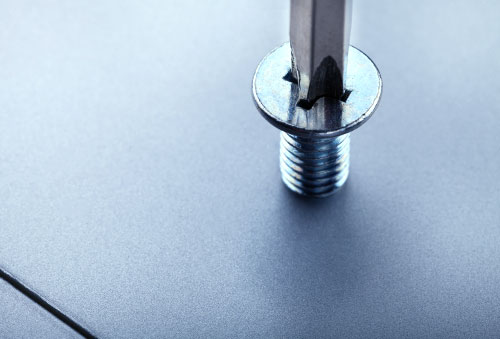 Lähikuva metallilevystä ja ruuvista jota kiinnitetään levyyn.