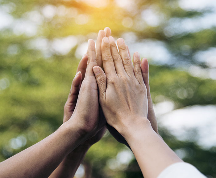 Lähikuva neljän henkilön yhteen tuoduista käsistä.