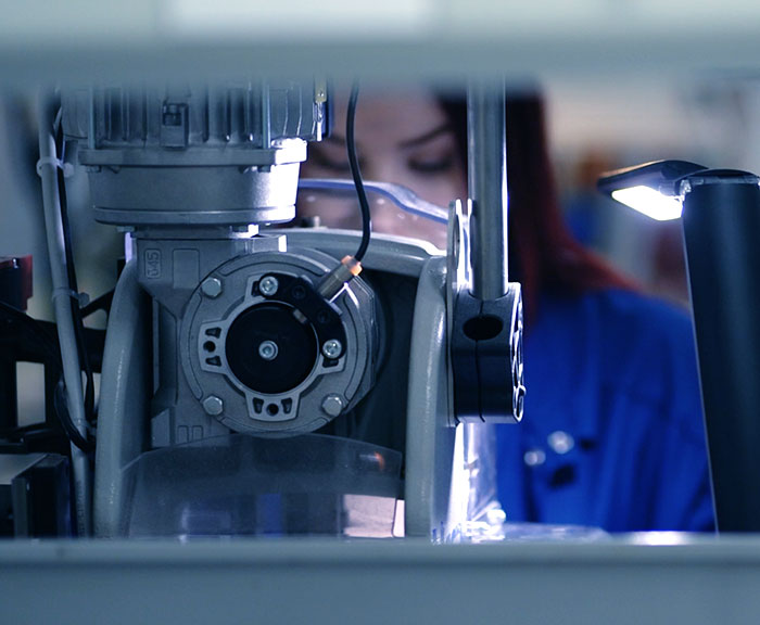 Nainen työskentelee laitteen takana kohdelampun valossa.