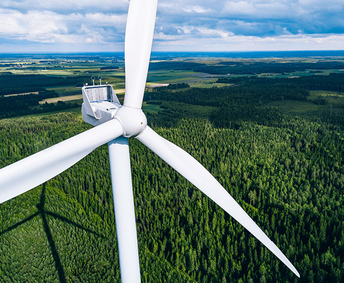 Kuvassa tuulivoimala ja taustalla metsämaisema.